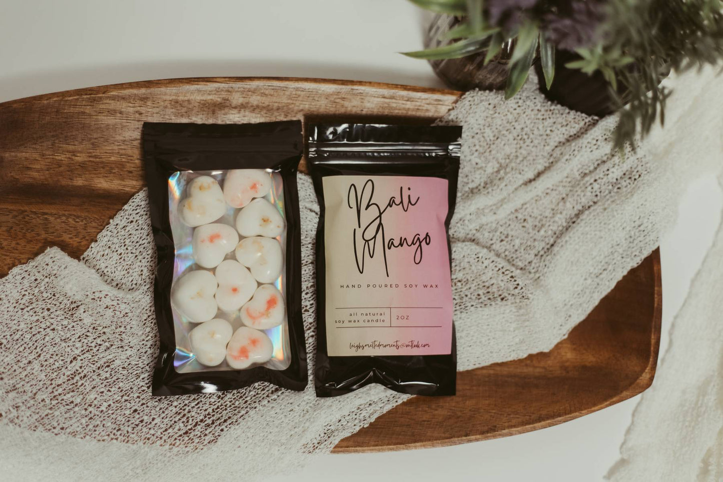 Bali Mango hand-poured soy wax melts in black resealable packaging on a wooden tray with a textured cloth.