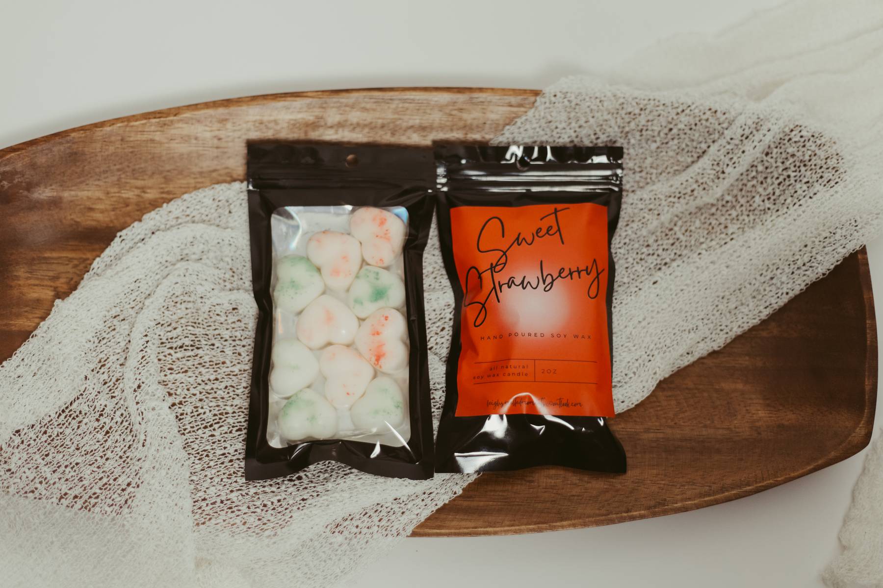 Sweet Strawberry hand-poured soy wax melts in black resealable packaging with heart-shaped wax pieces on a wooden tray.