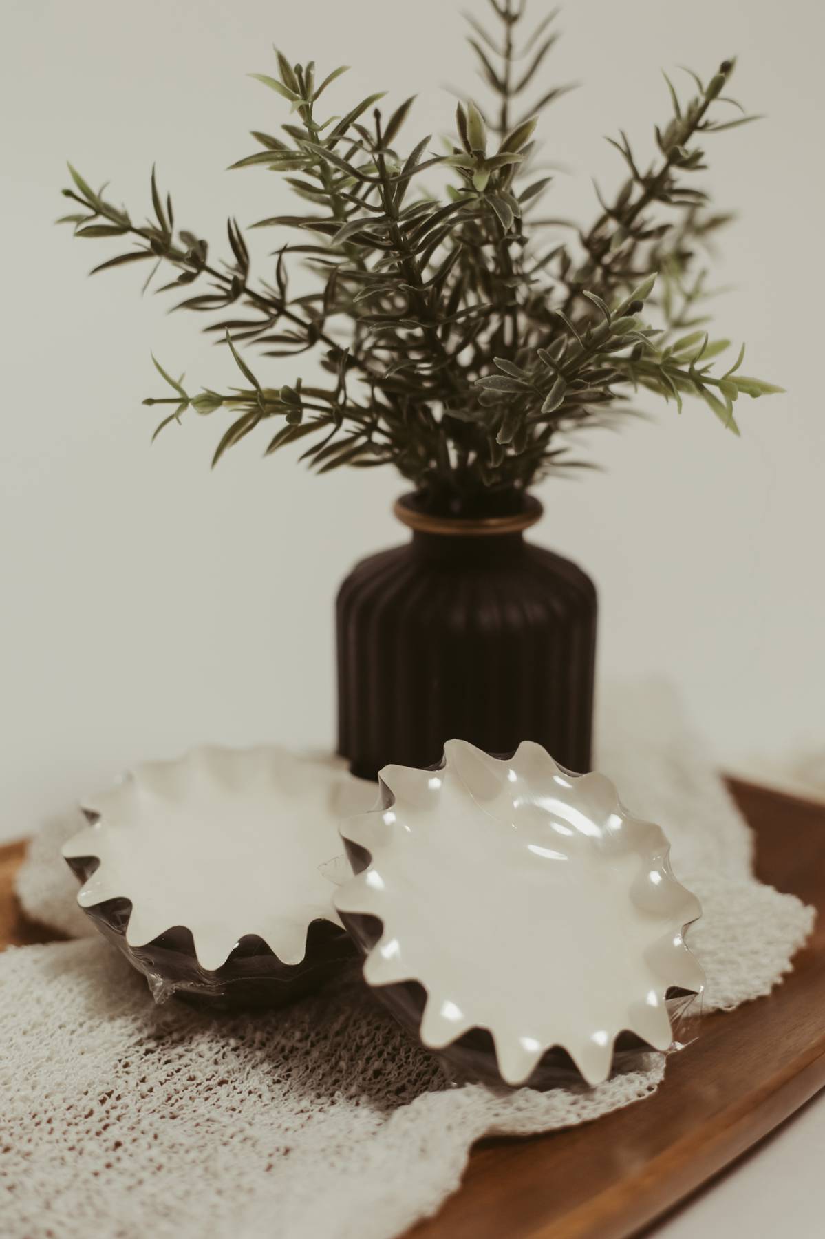 Close-up of reusable wax melt liners with a fluted design on a wooden tray with a decorative plant.