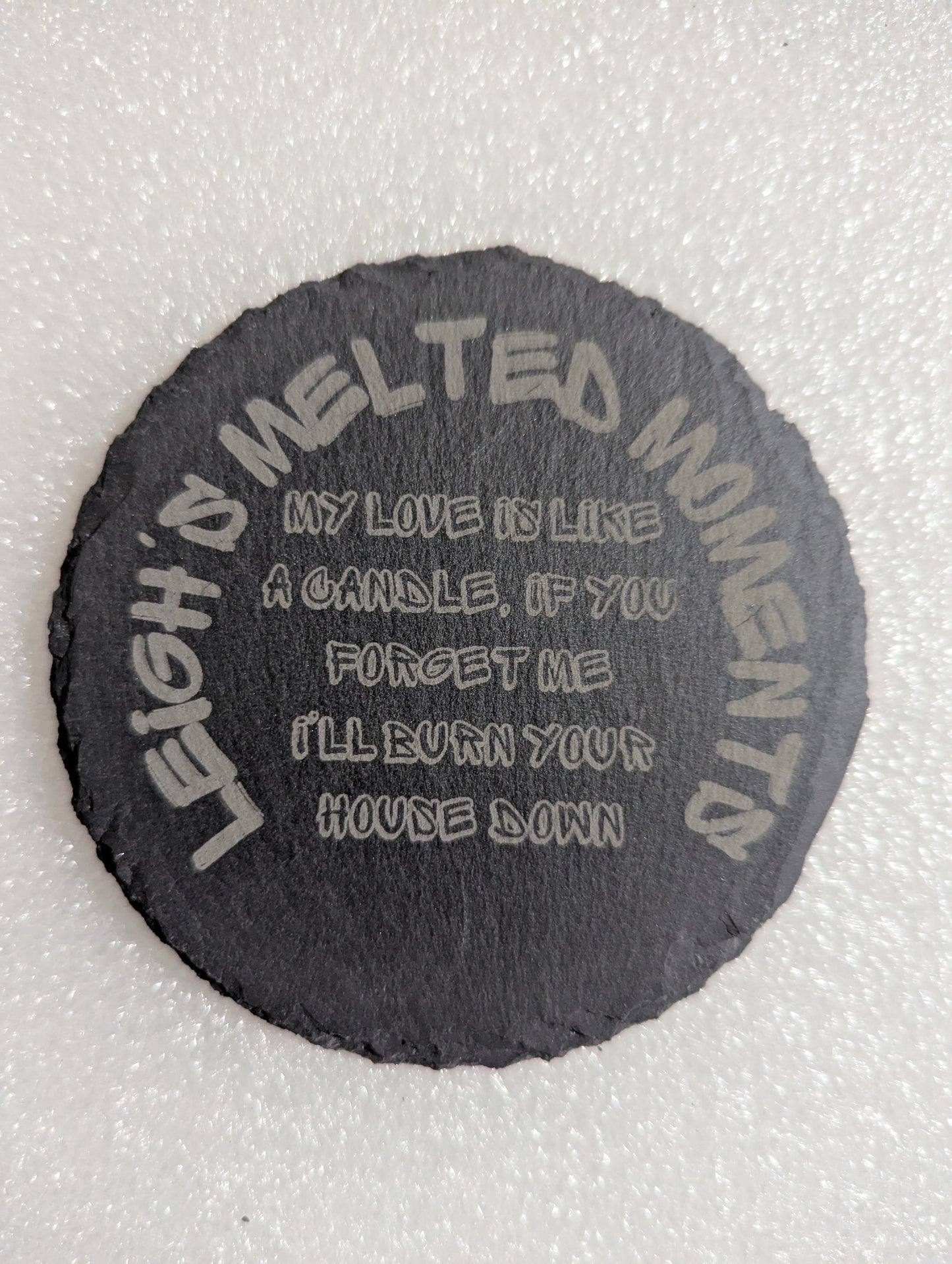 Engraved slate coaster with humorous text: 'My love is like a candle, if you forget me I'll burn your house down' and 'Leigh's Melted Moments' branding.