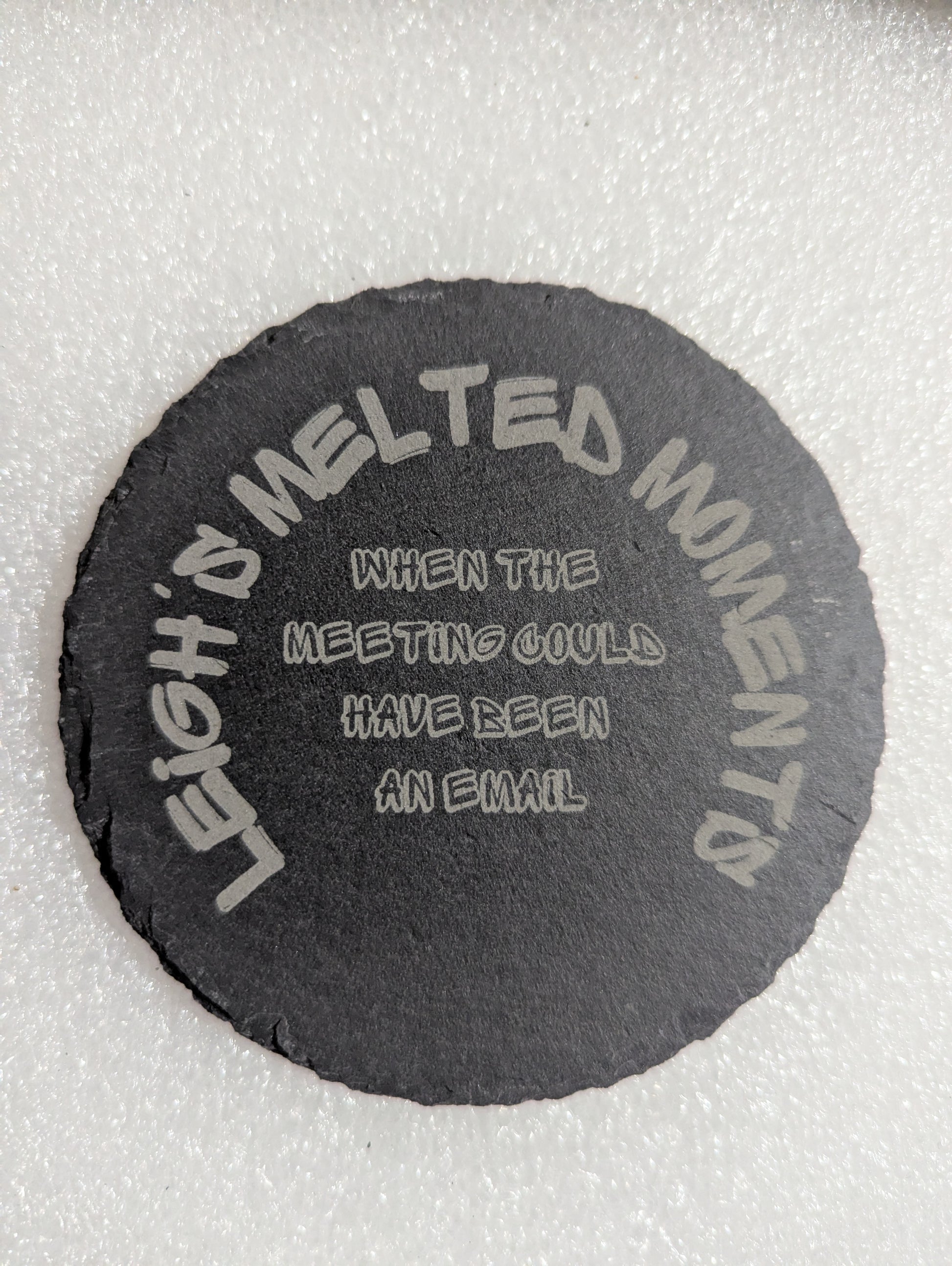 Black slate coaster engraved with the phrase 'When the meeting could have been an email' and 'Leigh's Melted Moments' branding.
