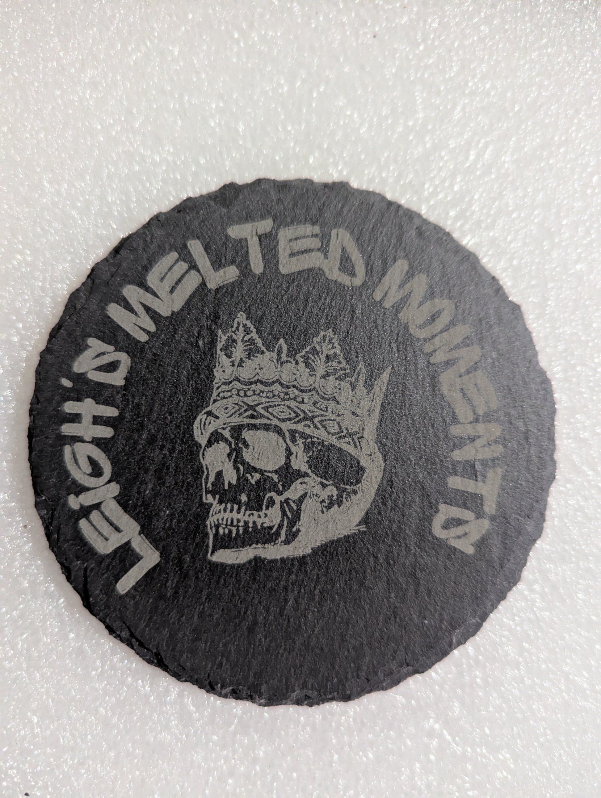 Black slate coaster featuring an engraved skull wearing a crown, with 'Leigh's Melted Moments' branding around the edge.